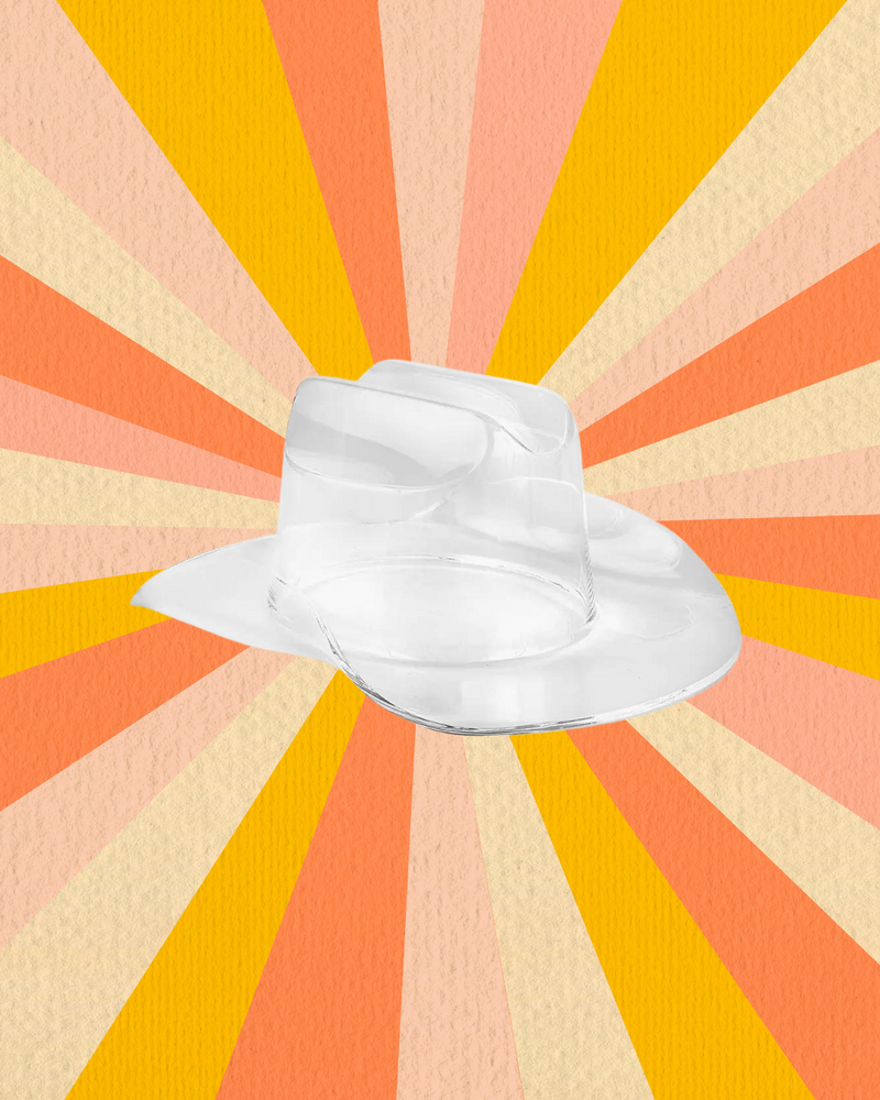 A clear acrylic cowboy hat bowl set against a vibrant, sunburst background of orange, yellow, and cream shades.