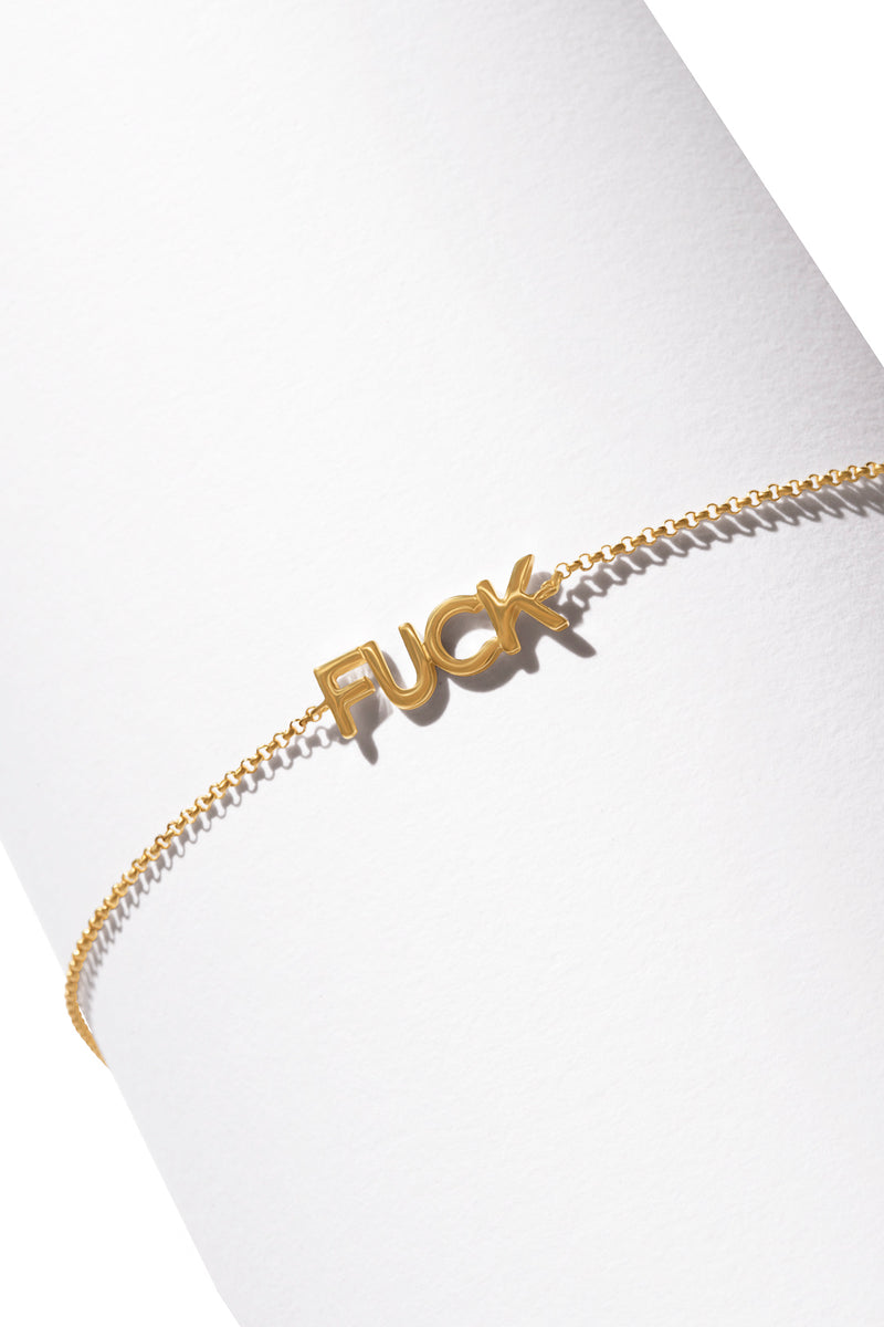 A 14K gold bracelet featuring a curse word charm in the middle. 