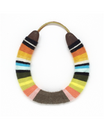 A lucky horseshoe that is wrapped in a multi-colored yarn.