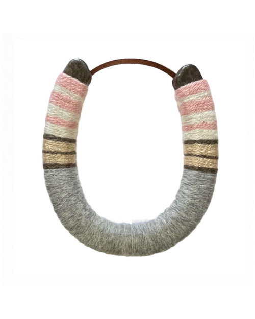 A lucky horseshoe that is wrapped in a multi-colored yarn.