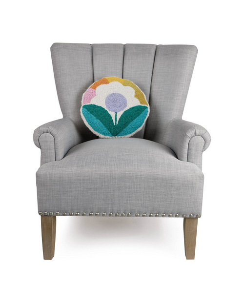 A cozy grey armchair adorned with a round sunflower pillow, featuring a multicolored design that brings a lively and whimsical feel to any room. 