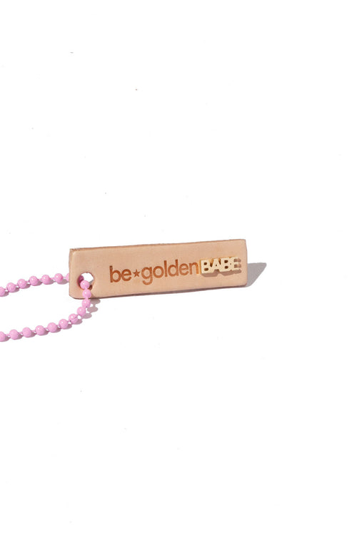 Tan leather keychain with the phrase 'be golden' engraved, 14k yellow gold babe stud is attached